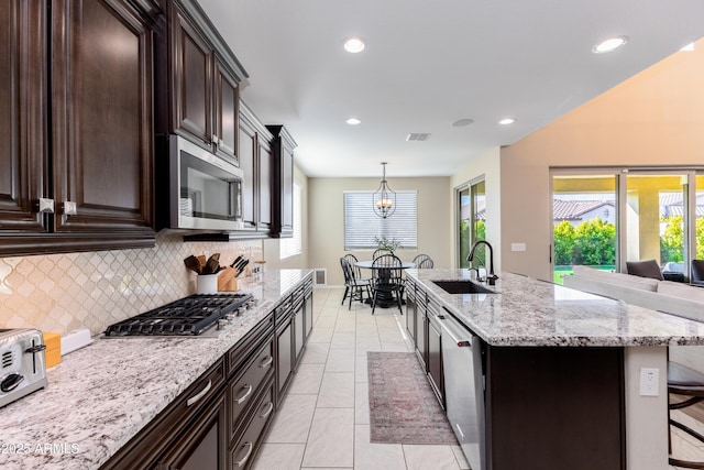 kitchen featuring an island with sink, sink, backsplash, appliances with stainless steel finishes, and a kitchen breakfast bar