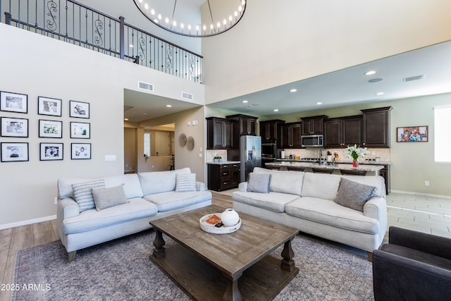 living room with an inviting chandelier, a towering ceiling, and hardwood / wood-style floors