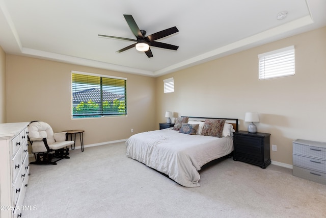 bedroom featuring a raised ceiling, multiple windows, and light colored carpet