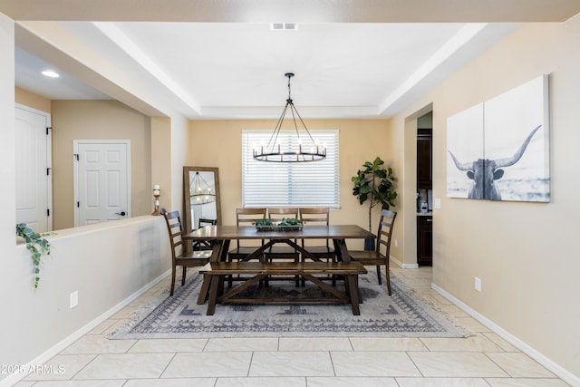 dining room with light tile patterned flooring, an inviting chandelier, and a tray ceiling