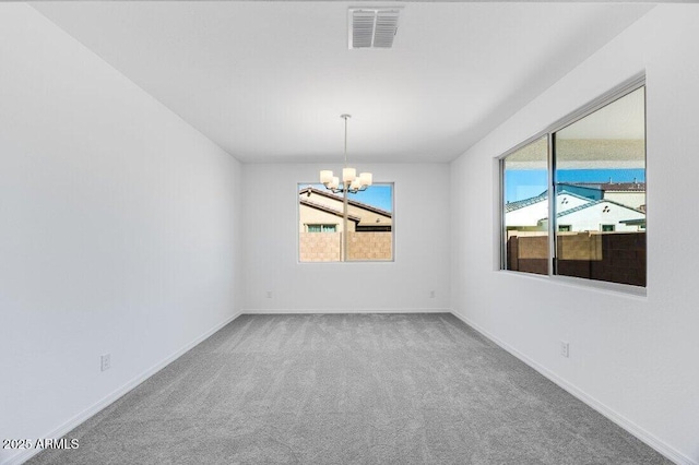 unfurnished room with carpet, visible vents, baseboards, and an inviting chandelier