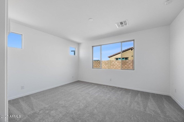 empty room featuring carpet floors, visible vents, and plenty of natural light