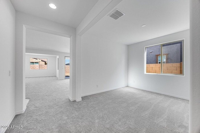 unfurnished room with carpet, visible vents, and baseboards