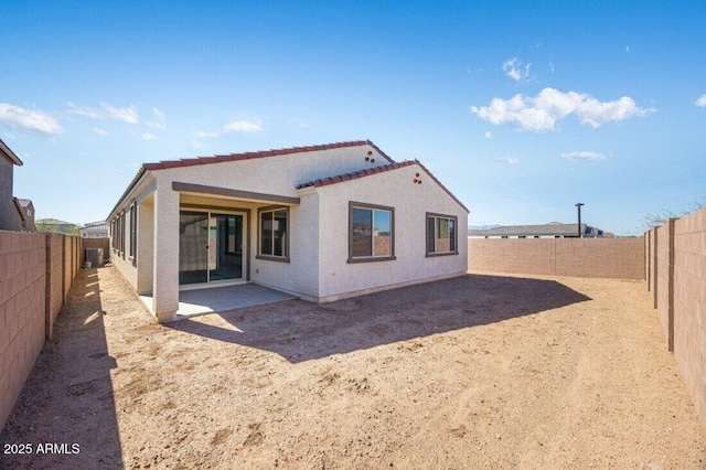 rear view of house with a fenced backyard, a patio, and stucco siding