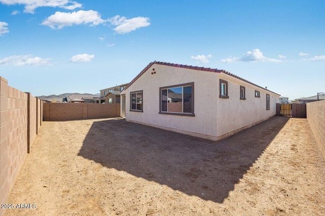 rear view of property featuring a fenced backyard and stucco siding