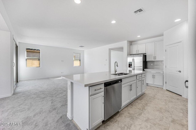 kitchen with visible vents, open floor plan, a kitchen island with sink, stainless steel appliances, and a sink