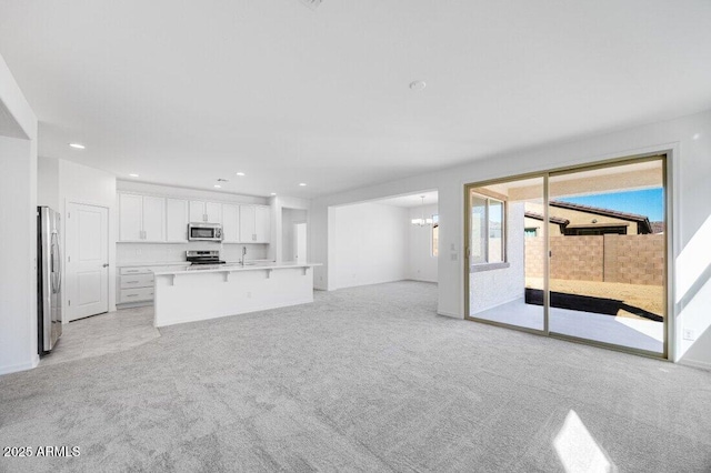 unfurnished living room with a chandelier, recessed lighting, and light colored carpet