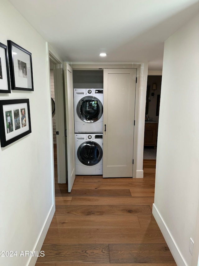 laundry room with hardwood / wood-style floors and stacked washing maching and dryer