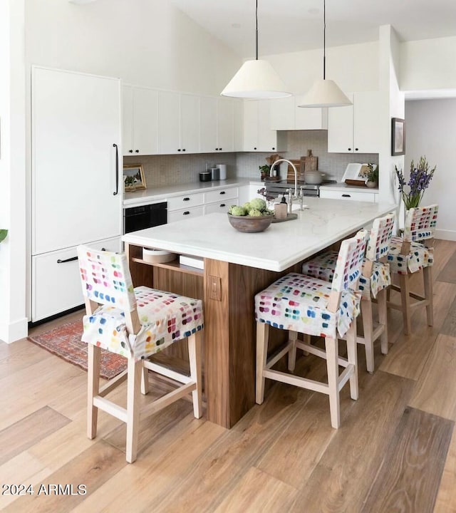 kitchen with white cabinetry, tasteful backsplash, white fridge, pendant lighting, and light wood-type flooring