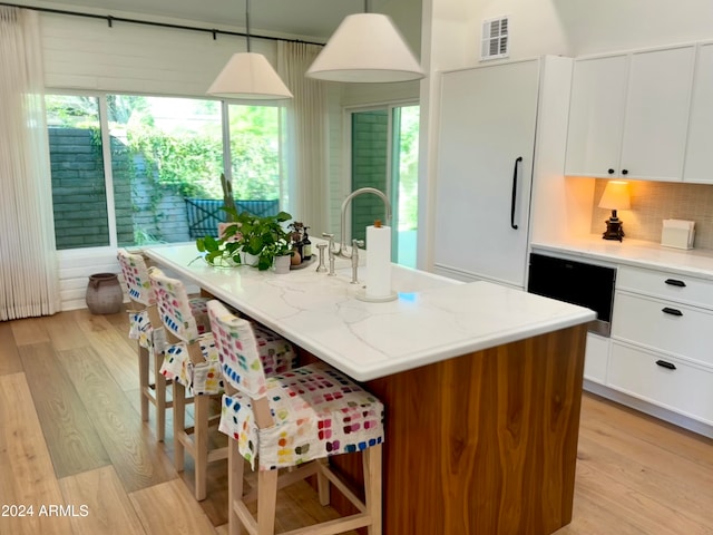 kitchen featuring decorative light fixtures, a center island with sink, and plenty of natural light