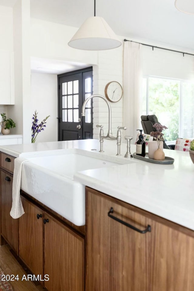 kitchen featuring dark wood-type flooring, white cabinetry, sink, and hanging light fixtures