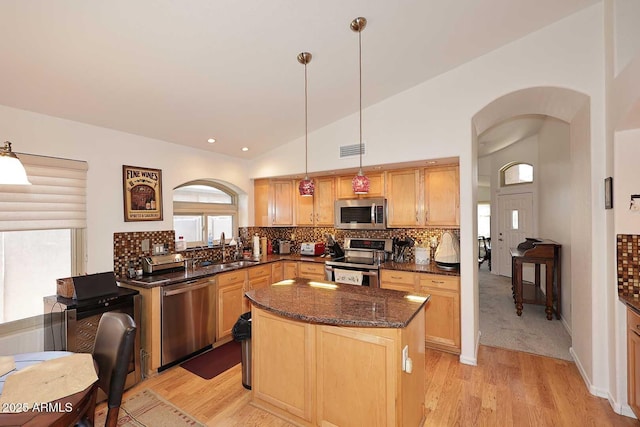 4506 E Lone Cactus Dr, Phoenix, AZ 85050 - kitchen with stainless steel appliances, a sink, arched walkways, light wood finished floors, and dark stone countertops