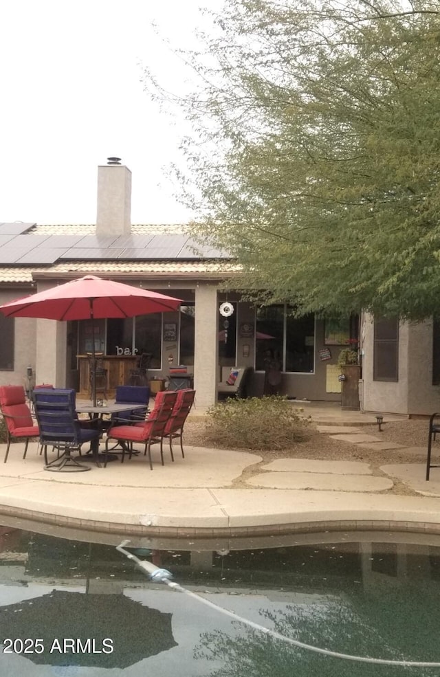 rear view of property with a patio area and solar panels