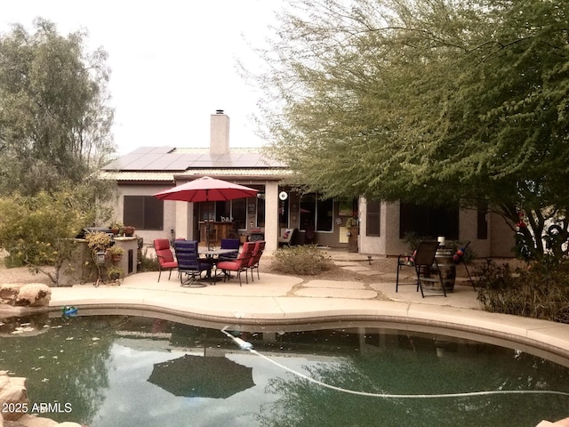 rear view of property with a patio area and solar panels