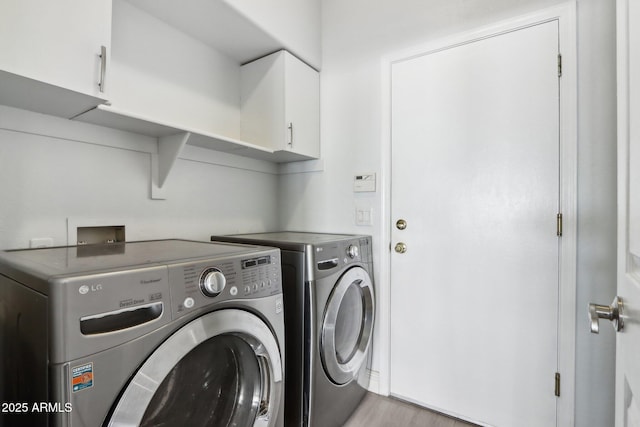 laundry area with cabinets, independent washer and dryer, and light wood-type flooring