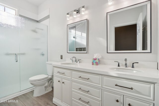 bathroom featuring vanity, a shower with shower door, and toilet