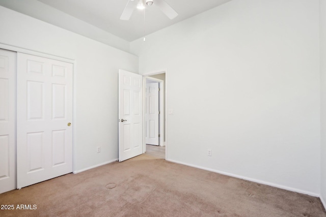 unfurnished bedroom with ceiling fan, light colored carpet, and a closet