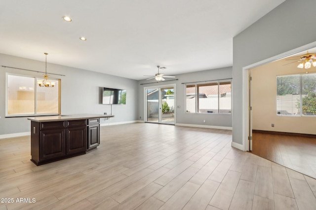 unfurnished living room with ceiling fan with notable chandelier