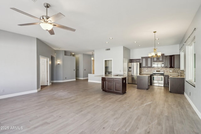 kitchen with appliances with stainless steel finishes, a center island, dark brown cabinets, and pendant lighting