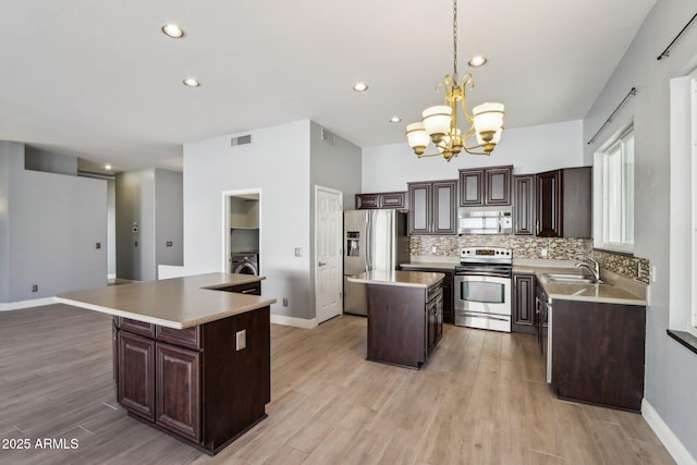 kitchen featuring sink, hanging light fixtures, stainless steel appliances, a notable chandelier, and a kitchen island