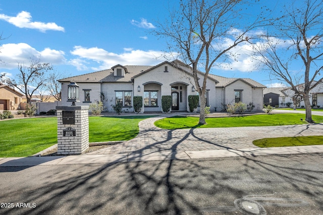 french provincial home with driveway, a residential view, a tiled roof, a front lawn, and stucco siding