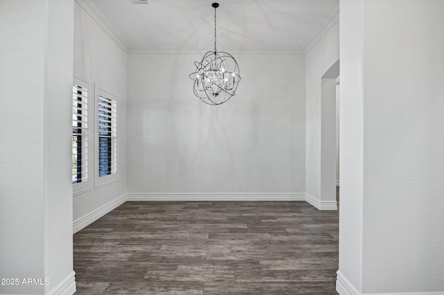 empty room featuring dark wood-style floors, crown molding, baseboards, and an inviting chandelier