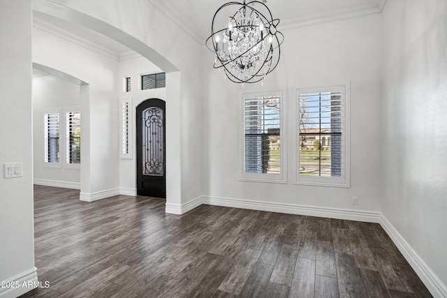 entrance foyer featuring arched walkways, dark wood-style flooring, a wealth of natural light, and crown molding