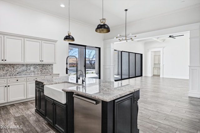 kitchen with wood finish floors, decorative light fixtures, open floor plan, a kitchen island with sink, and white cabinets