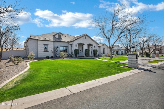 french country inspired facade with a tile roof, a front yard, fence, and a residential view