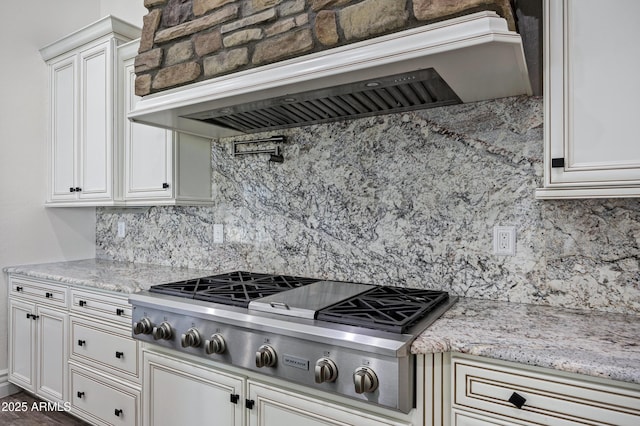 kitchen featuring tasteful backsplash, stainless steel gas cooktop, custom exhaust hood, and light stone countertops