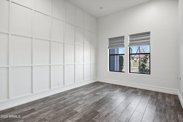 spare room with dark wood-style flooring and baseboards