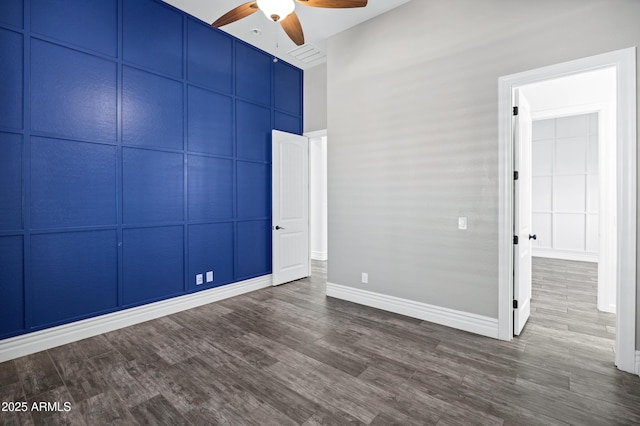 spare room with ceiling fan, dark wood-style flooring, and baseboards