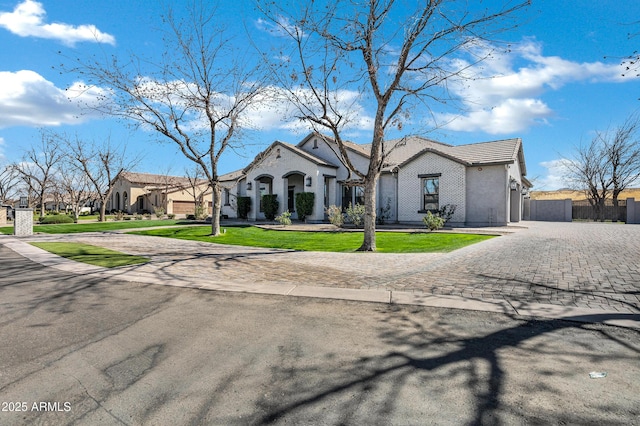 view of front of property with fence, decorative driveway, a residential view, stucco siding, and a front yard