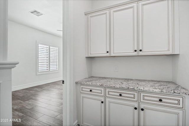 kitchen featuring light stone countertops, baseboards, visible vents, and dark wood finished floors