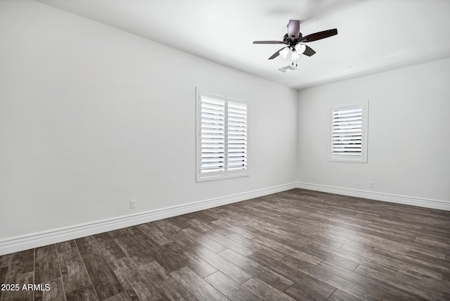 spare room featuring dark wood-style floors, visible vents, ceiling fan, and baseboards