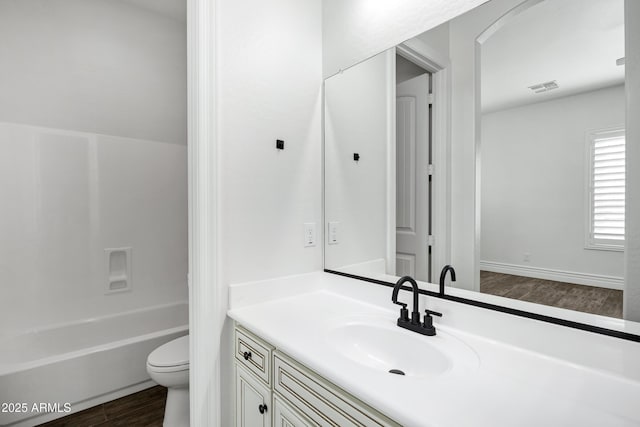 full bath with visible vents, toilet, vanity, wood finished floors, and shower / bathtub combination