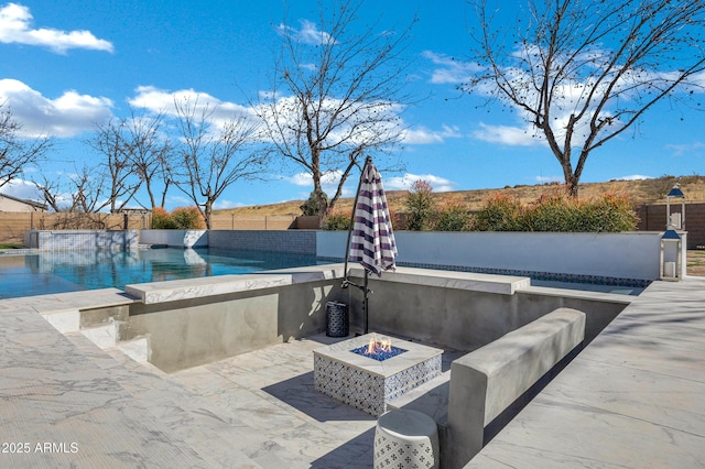 view of swimming pool featuring a fenced in pool, a patio area, fence, and a fire pit