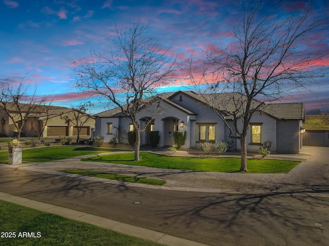 view of front of home featuring a lawn, driveway, and stucco siding