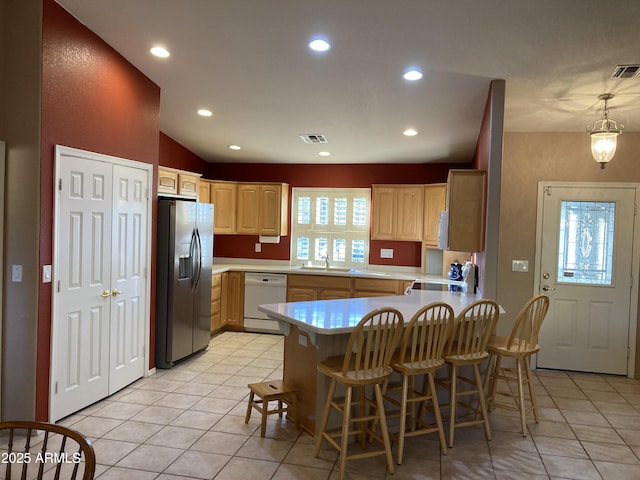 kitchen featuring dishwasher, stainless steel refrigerator with ice dispenser, light tile patterned floors, light brown cabinetry, and a kitchen bar