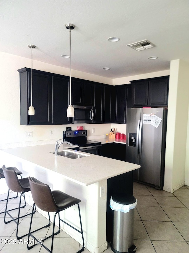 kitchen with kitchen peninsula, hanging light fixtures, light tile patterned floors, and stainless steel appliances