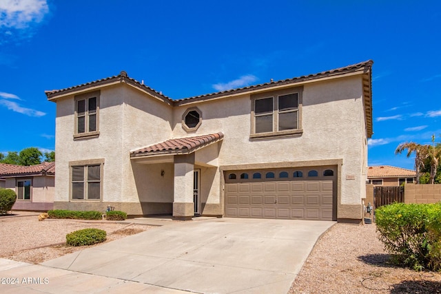 mediterranean / spanish-style home featuring stucco siding, a tile roof, an attached garage, and fence