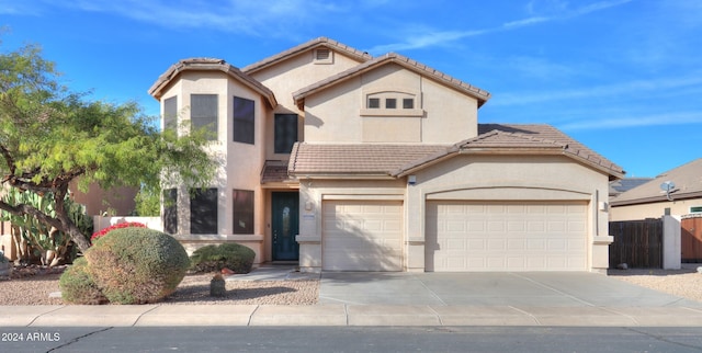 mediterranean / spanish house with a tile roof, stucco siding, concrete driveway, fence, and a garage