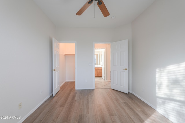 unfurnished bedroom featuring a closet, a spacious closet, ceiling fan, and light hardwood / wood-style flooring