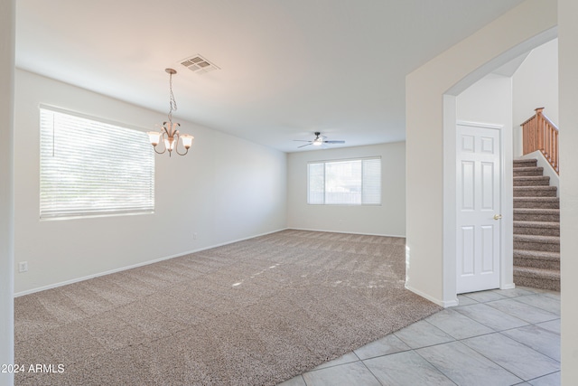 spare room with ceiling fan with notable chandelier and light tile patterned floors