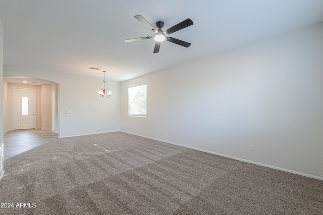 carpeted empty room featuring ceiling fan with notable chandelier