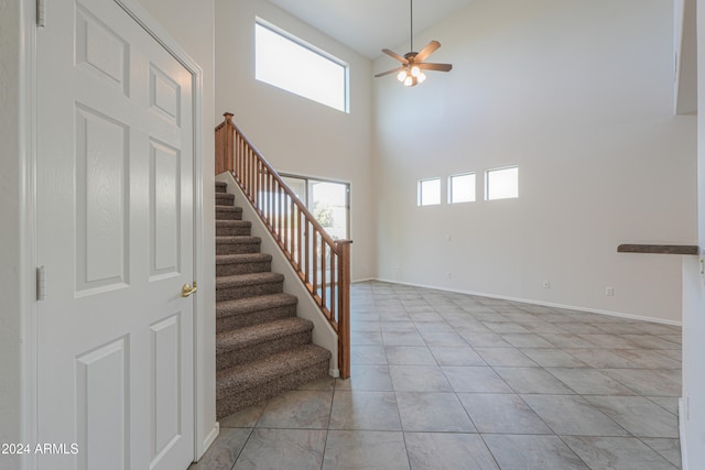 stairs featuring ceiling fan, plenty of natural light, a high ceiling, and tile patterned flooring