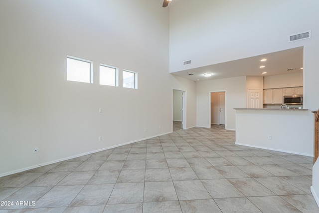 unfurnished living room featuring light tile patterned floors and a towering ceiling