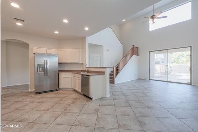 kitchen with white cabinetry, sink, ceiling fan, a high ceiling, and appliances with stainless steel finishes