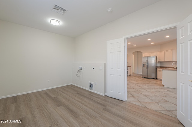 clothes washing area featuring washer hookup, light hardwood / wood-style flooring, and electric dryer hookup