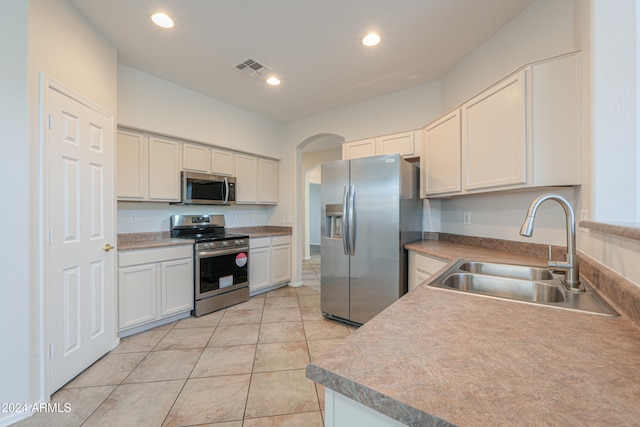 kitchen with white cabinets, light tile patterned floors, stainless steel appliances, and sink